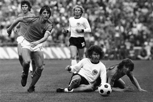 This is a July 7, 1974  file photo  of Dutch forward Johan Cruyff, left, runs past German defender Paul Breitner, sitting on the pitch  during the final of the Soccer World Cup at the Olympic Stadium in Munich, Germany. Dutch soccer great Johan Cruyff, who revolutionized the game with the concept of 'Total Football,' died Thursday March 24, 2016. He was 68. (AP Photo)