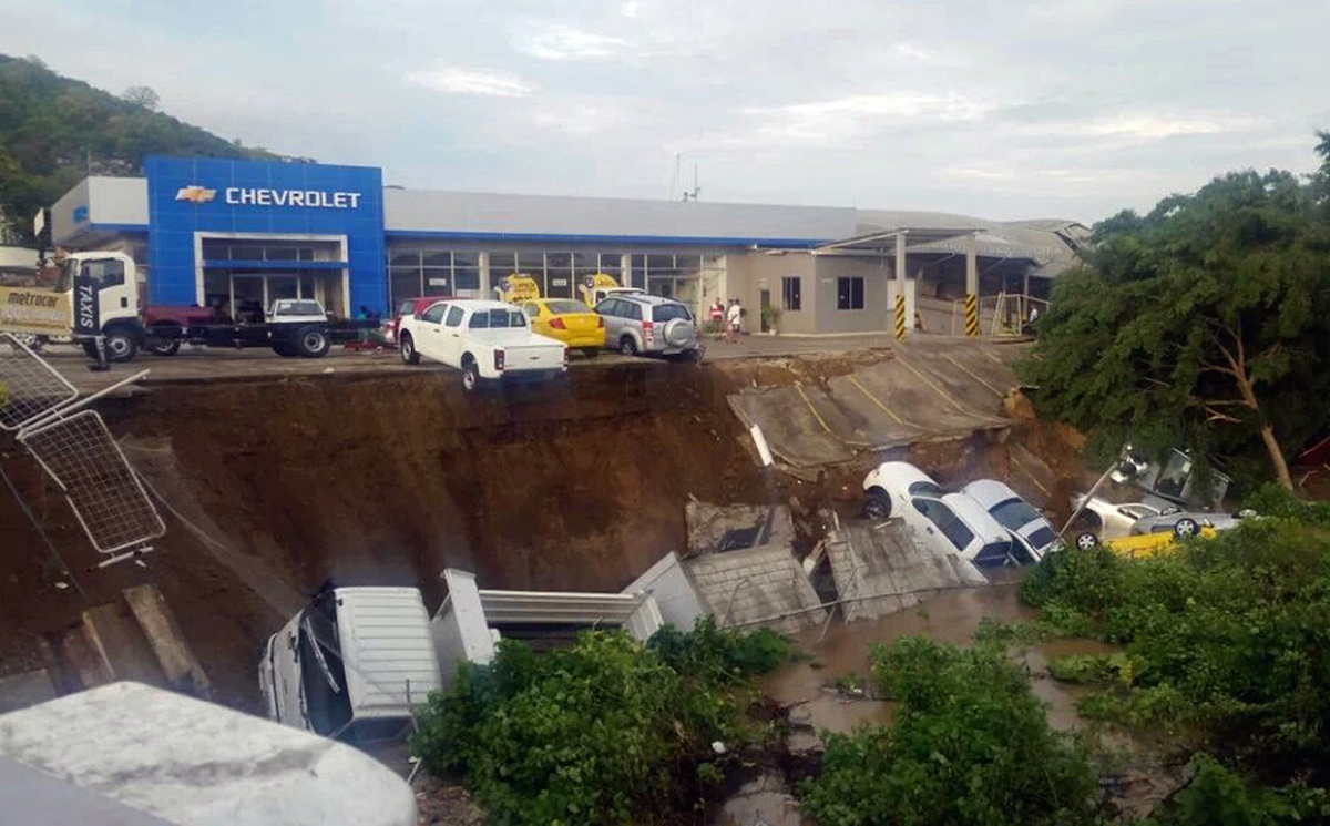 Vehicles from a car dealership hang on a precipice caused by an earthquake induced landslide in Portoviejo, Ecuador, Sunday, April 17, 2016. The strongest earthquake to hit Ecuador in decades flattened buildings and buckled highways along its Pacific coast, sending the Andean nation into a state of emergency. (AP Photo/Juan Fernando Molina)