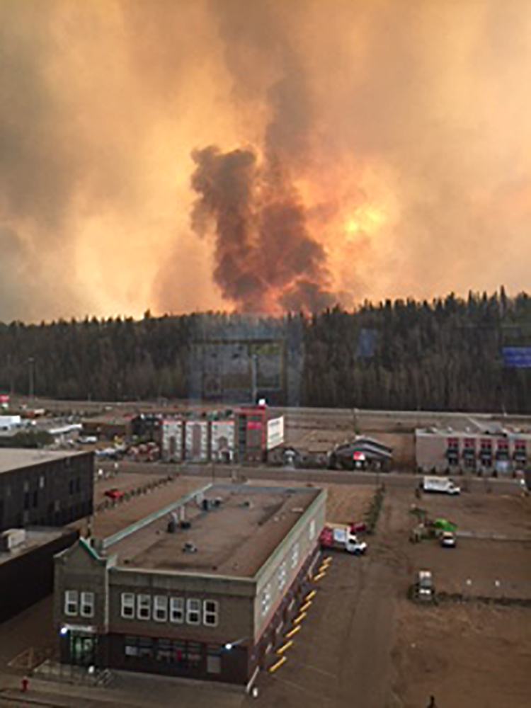 This handout photograph obtained courtesy of the Alberta Agriculture and Forestry Department shows smoke rising from a heavily wooded area on May 3, 2016 in the Canadian city of Fort McMurray, where most of the 100,000 residents were ordered to leave town when the blaze swept through the oil sands region, in what is Alberta province's largest ever evacutation. "All of Fort McMurray is under a mandatory evacuation order," Alberta emergency services announced, after previously indicating that the northern edge of the fire was "growing rapidly." / AFP PHOTO / Lynn Daina