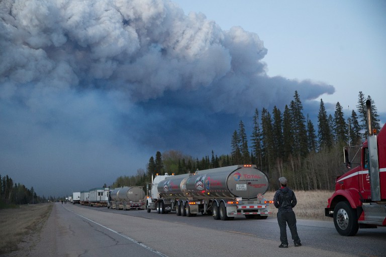 FORT MCMURRAY, AB - MAY 05: Drivers wait for clearance to take firefighting supplies into town on May 05, 2016 outside of Fort McMurray, Alberta. Wildfires, which are still burning out of control, have forced the evacuation of more than 80,000 residents from the town. Scott Olson/Getty Images/AFP