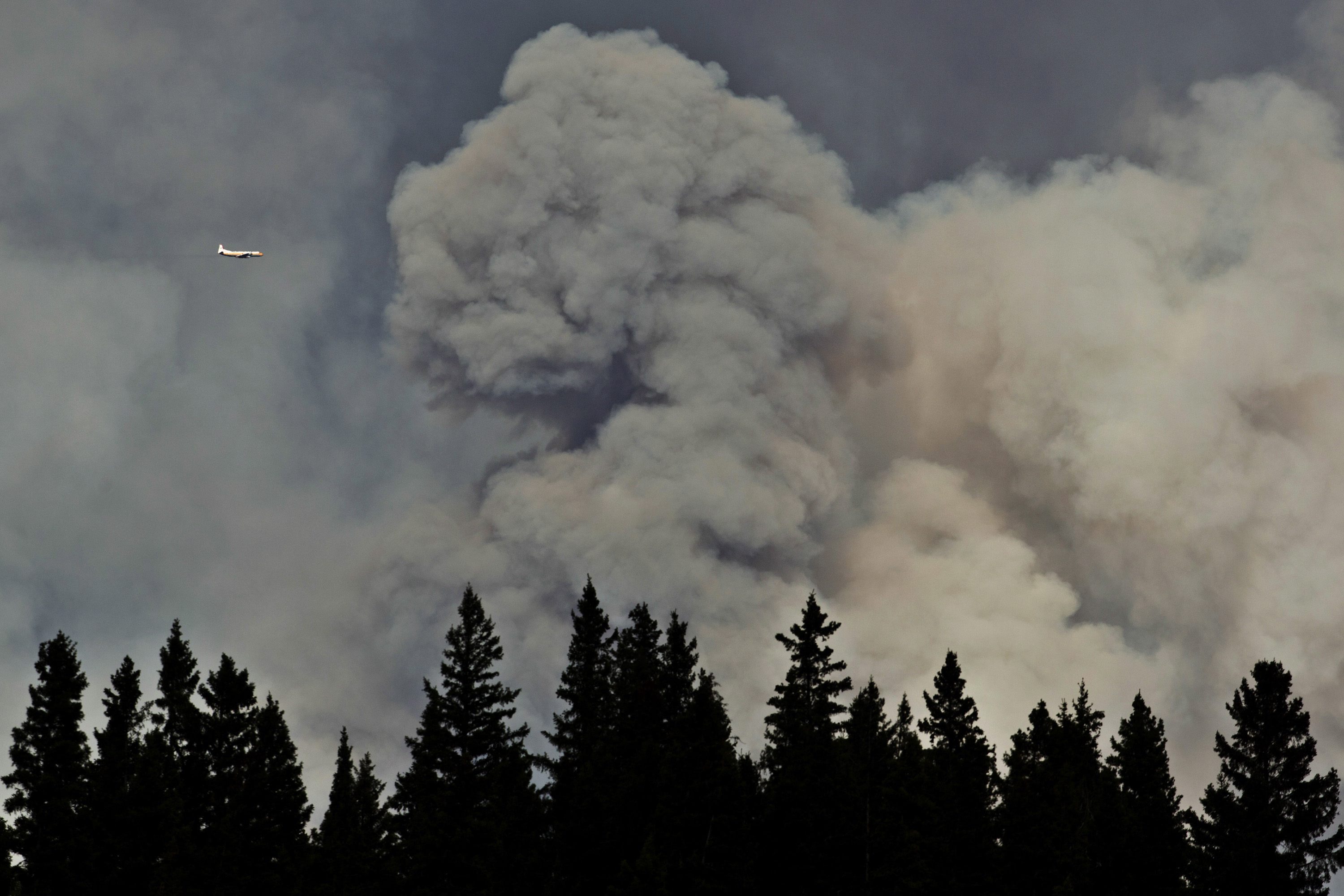 A plane surveys the area near a wildfire in Fort McMurray, Alberta, on Thursday, May 5, 2016. An ever-changing, volatile situation is fraying the nerves of residents and officials alike as a massive wildfire continues to bear down on the Fort McMurray area of northern Alberta. The province of Alberta declared a state of emergency. (Jason Franson/The Canadian Press via AP) MANDATORY CREDIT
