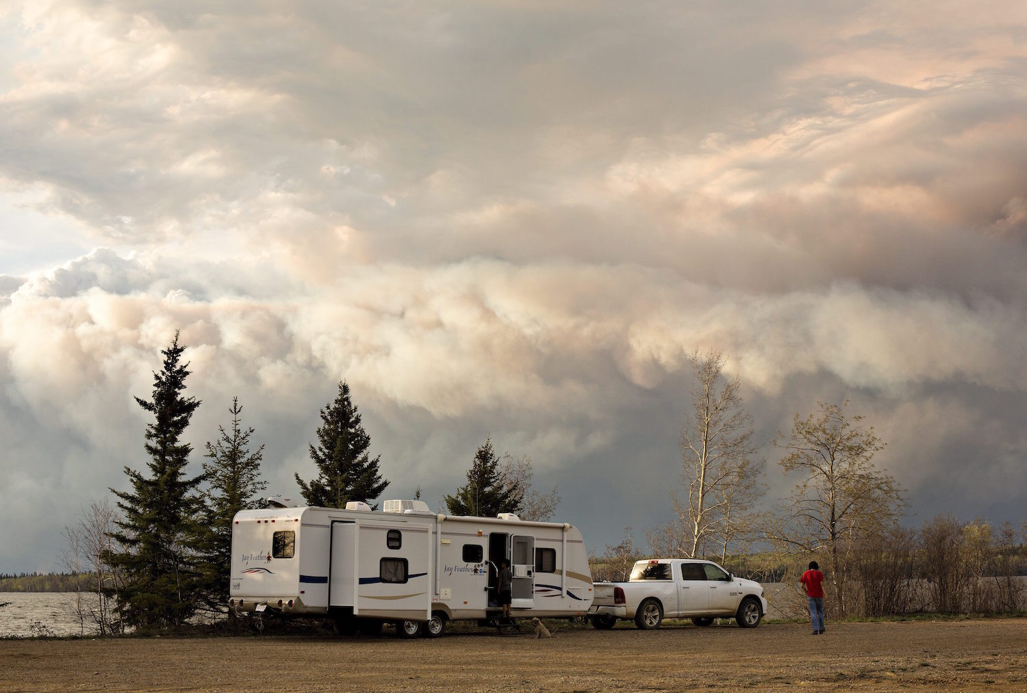 Evacuees camp by a lake as smoke fills the sky near Fort McMurray, Alberta, on Wednesday, May 4, 2016. Alberta declared a state of emergency Wednesday as crews frantically held back wind-whipped wildfires. No injuries or fatalities have been reported. (Jason Franson/The Canadian Press via AP) MANDATORY CREDIT