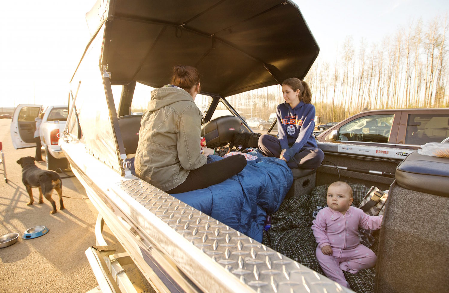 A family takes refuge in the back of their boat after evacuation at a rest stop near Fort McMurray, Alberta, Canada, on Wednesday, May 4, 2016. Thousands of residents were ordered to flee as flames moved into the Canadian oil sands city, destroying whole neighborhoods. (Jason Franson/The Canadian Press via AP) MANDATORY CREDIT