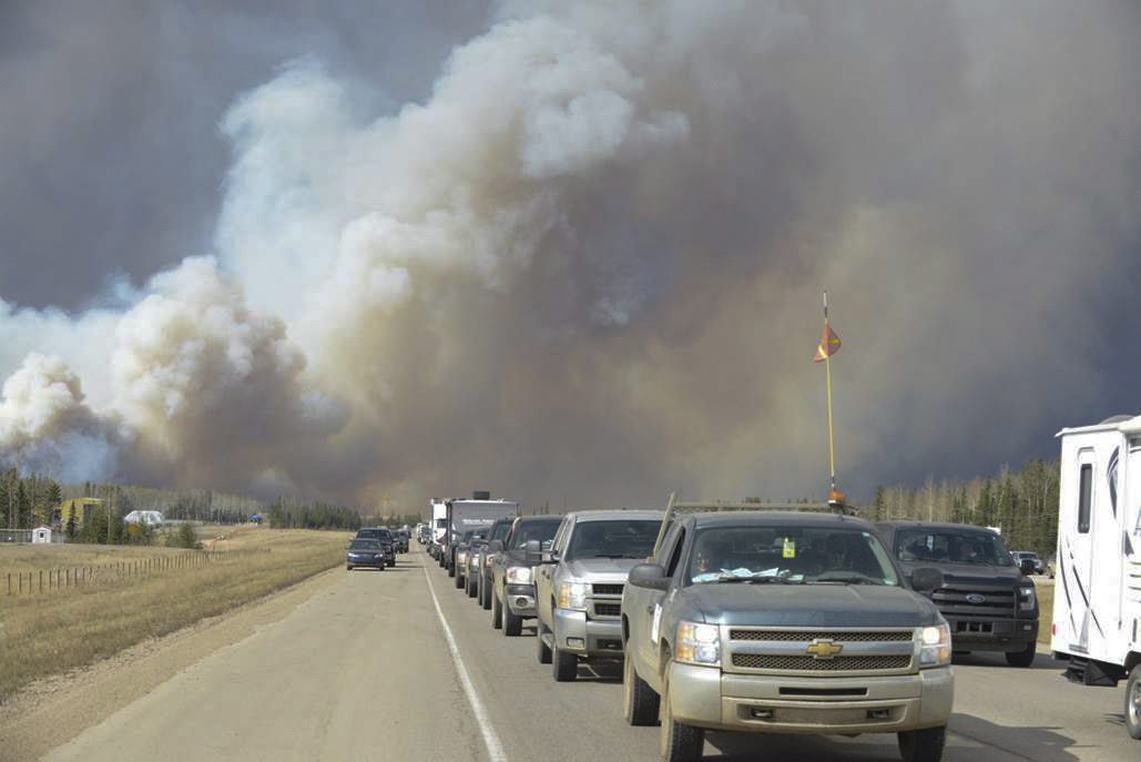 Smoke fills the air as people drive on a road in Fort McMurray, Alberta, Tuesday, May 3, 2016. (Greg Halinda/The Canadian Press via AP) 