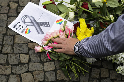 A man places his hand on a bunch of flowers  during a vigil in front of the United States embassy in Berlin, German, Monday, June 13, 2016  to honor the victims of the attack on the gay nightclub in Orlando, Fla. The vigil was organized by Berlin's lesbian and gay organization LSVD.   (AP Photo/Markus Schreiber)