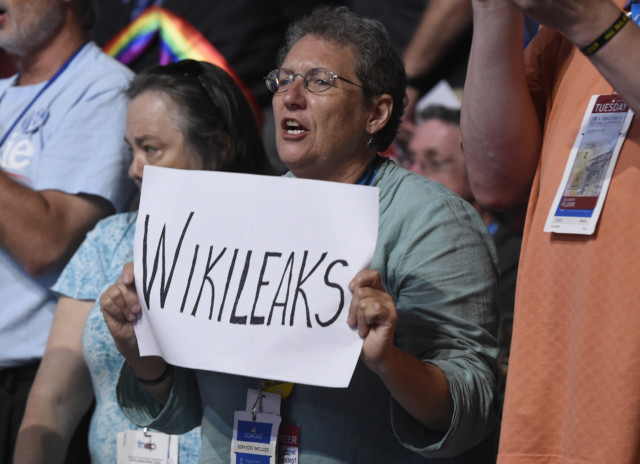 woman holds up a sign referencing Wikileaks
