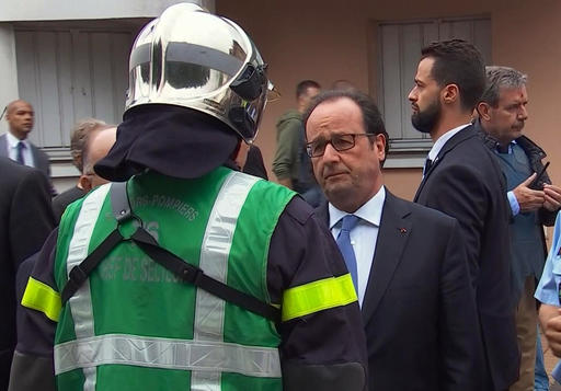In this grab made from video, French President Francois Hollande speaks with emergency services personnel after arriving at the scene of the hostage situation in Normandy, France, Tuesday, July 26, 2016. Two attackers took hostages inside a French church during morning Mass on Tuesday in the Normandy town of Saint-Etienne-du-Rouvray, killing an 86-year-old priest by slitting his throat before being shot and killed by police, French officials said. The Islamic State group claimed responsibility for the attack. (France Pool via AP)