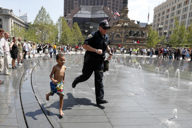 Police officer runs through a fountain with a small child