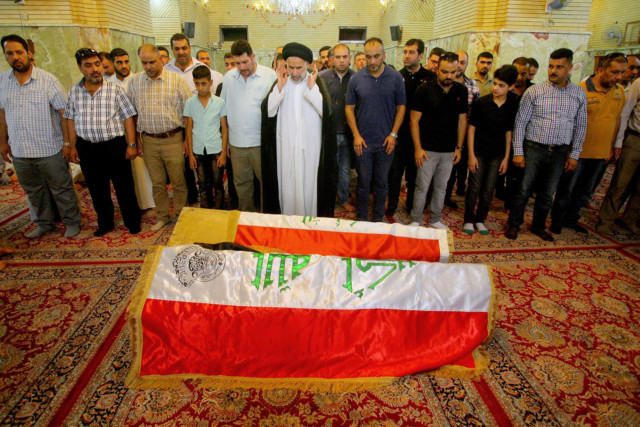 Mourners pray in front of the Iraqi flag-draped coffin