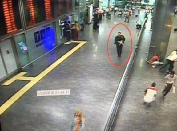 A still image from a closed-circuit camera shows a man believed to be one of the attackers walking inside the terminal carrying a weapon as bystanders and travellers run for cover at Istanbul airport, Turkey