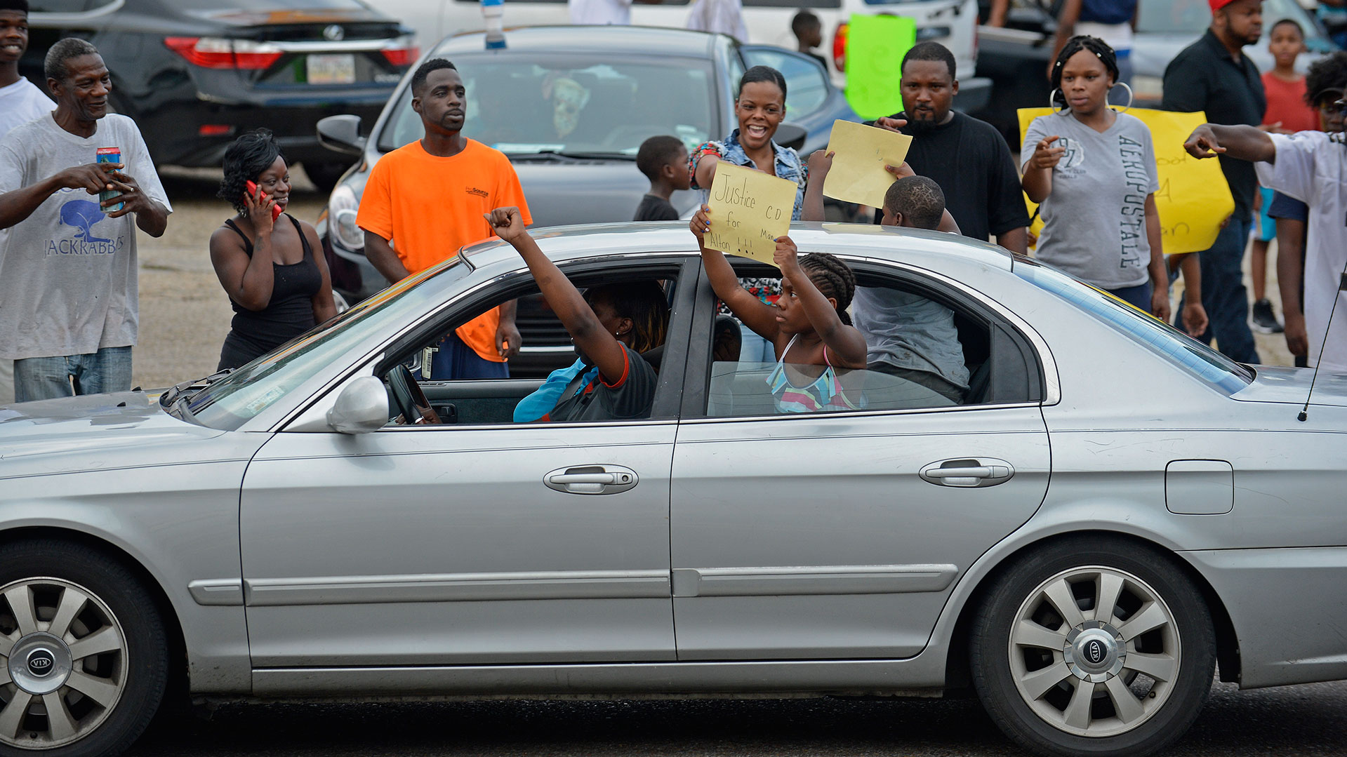 People gather in protest outside of the Triple S Food Mart on N. Foster at Fairfields Avenue, after the officer-involved fatal shooting of Alton Sterling on Tuesday, July 5, 2016, in Baton Rouge, La. An autopsy shows Sterling, 37, of Baton Rouge, died Tuesday of multiple gunshot wounds to the chest and back, said East Baton Rouge Parish Coroner Dr. William Clark. Officers responded to the store about 12:35 a.m. Tuesday after an anonymous caller indicated a man selling music CDs and wearing a red shirt threatened him with a gun, said Cpl. L'Jean McKneely. (Hilary Scheinuk/The Advocate via AP)