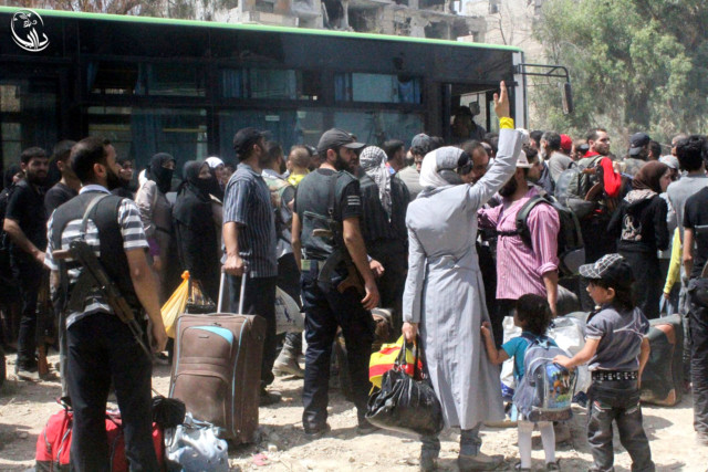 Syrian citizens gather with their belonging next of a bus, as they prepare to evacuate from Daraya, a blockaded Damascus suburb, on Friday, Aug. 26, 2016. (Local Council of Daraya City via AP)