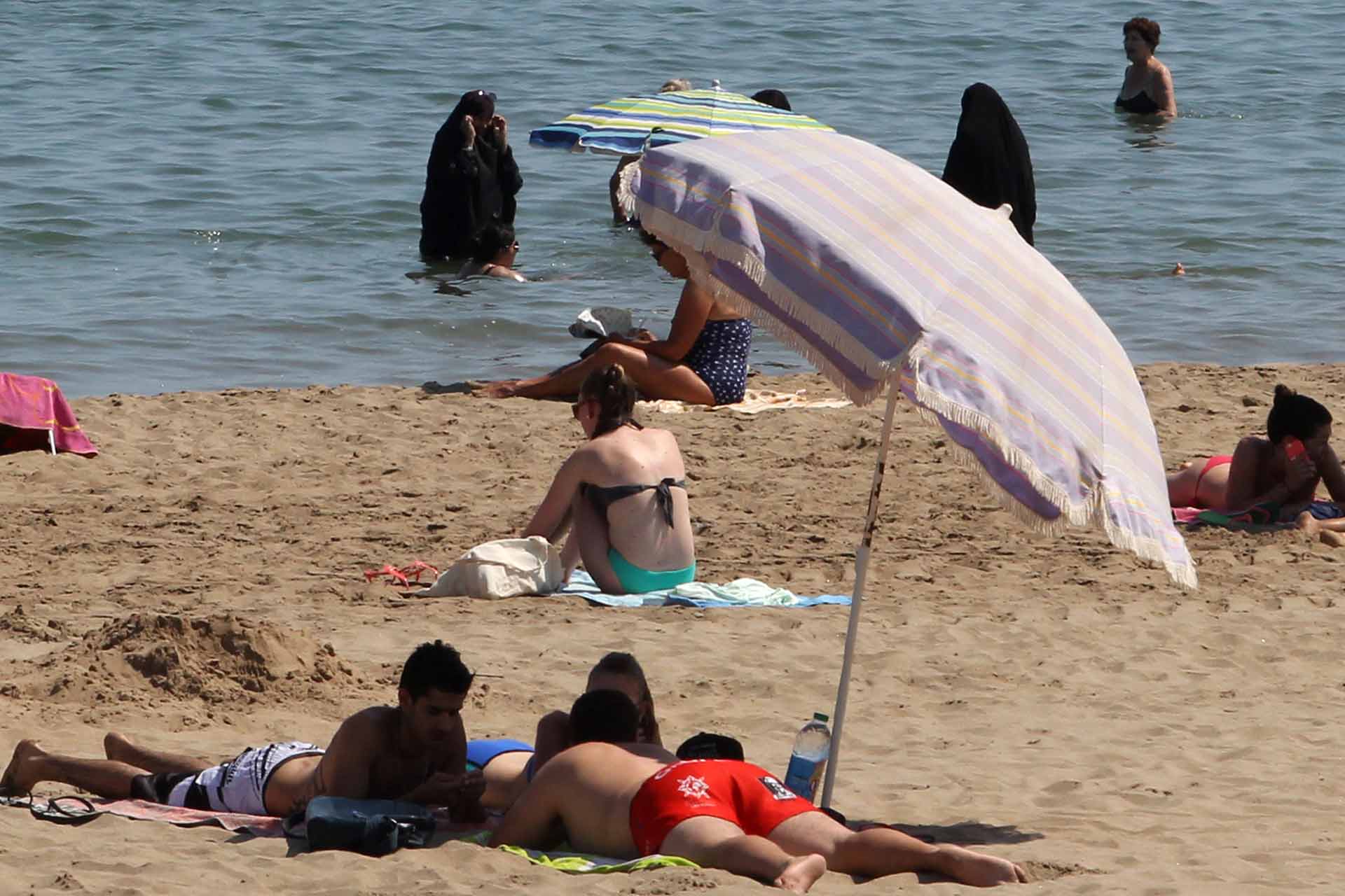 A photo taken on June 4, 2015 shows two Muslim women wearing chador as they enjoy their time with other people a beach of Narbonne, southern France. (AFP PHOTO / Raymond Roig)
