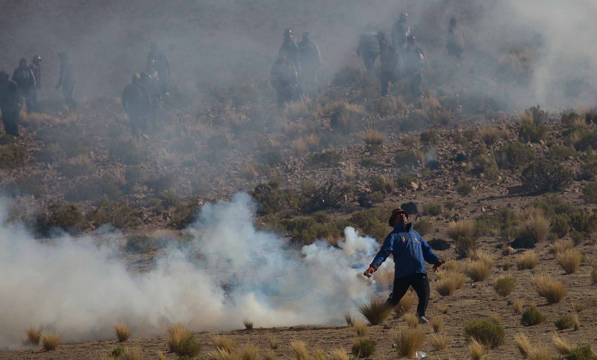 Independent miners clash with the police as they run from clouds of tear gas during protests in Panduro, Bolivia, Thursday, Aug. 25, 2016. Thousands of Independent miners continued their protests with roadblocks which precipitated the clashes as the police attempted to dislodge them. (AP Photo/Juan Karita)
