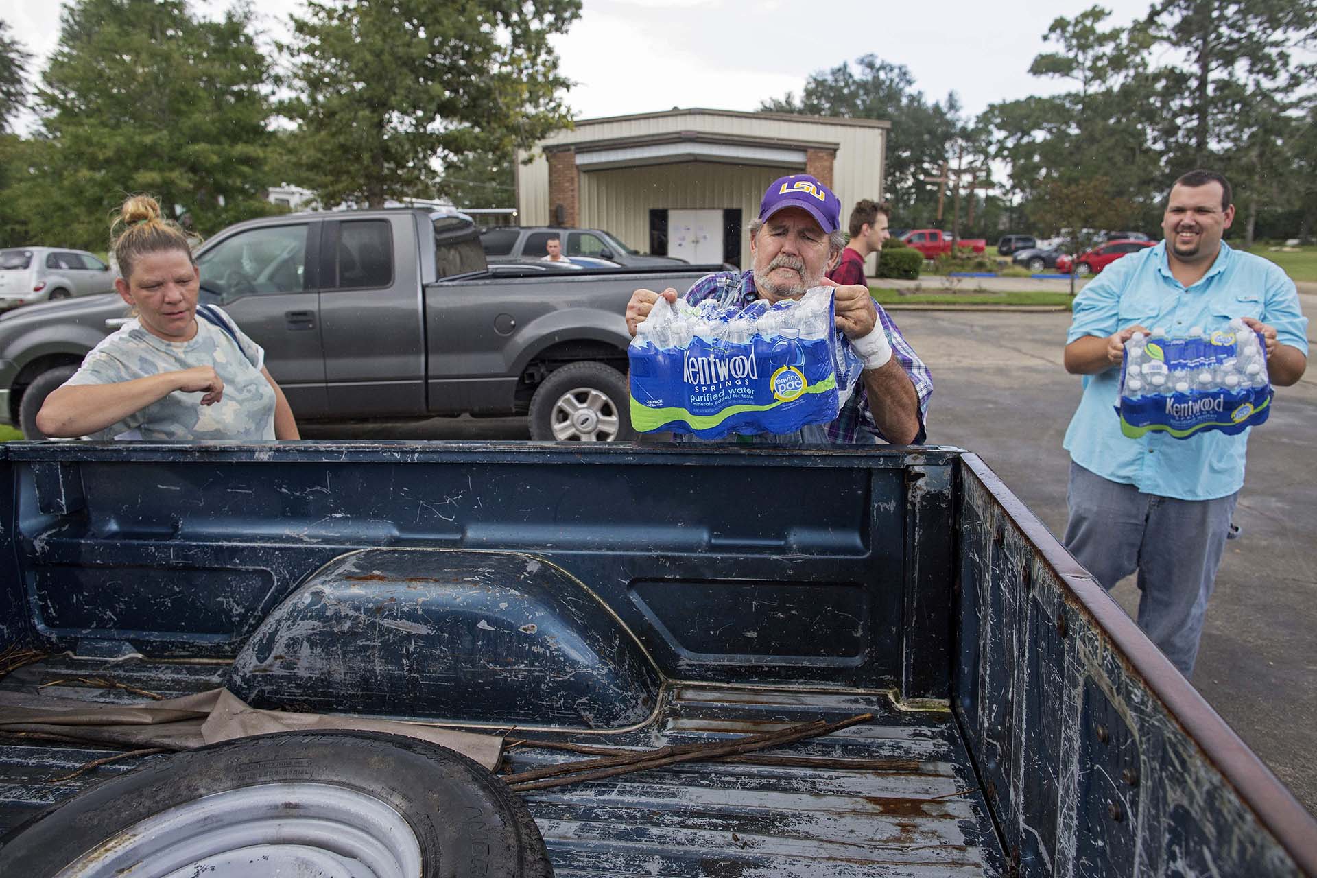 Robert Miller, 66, center, and Matt Decker, 33, right, loads water in the pickup of flood surviver Dawn Hay, 40, at South Walker Baptist Church in Walker, La., Sunday, Aug. 21, 2016. Hay said he is feeding several people taking refuge in her home and needs help supporting them after losing her job because the business closed after the flood. (AP Photo/Max Becherer)