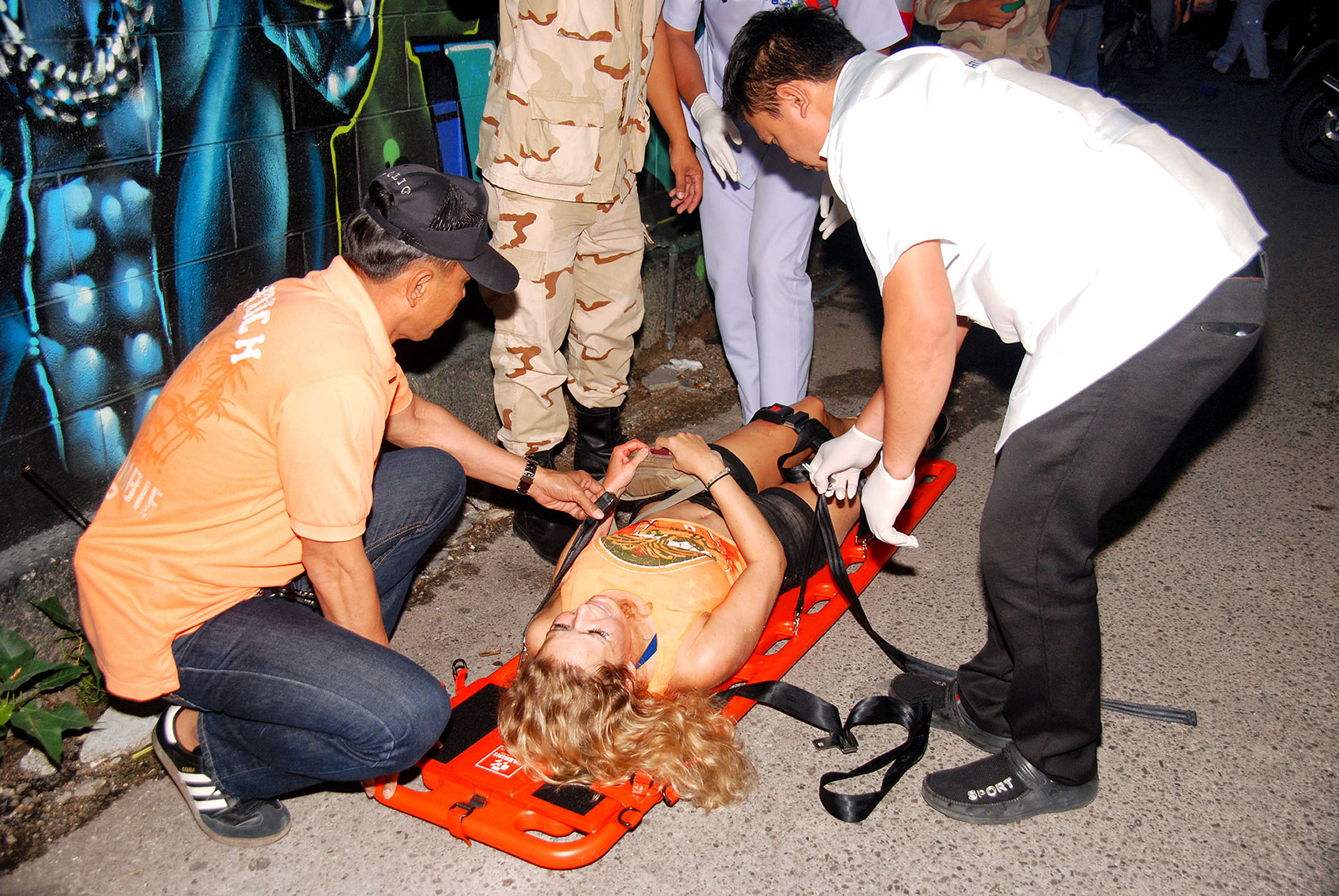 In this Thursday, Aug. 11, 2016, photo, an injured person is helped after a bomb blast in the southern resort city of Hua Hin, 240 kilometers (150 miles) south of Bangkok, Thailand. Police are investigating a series of bomb blasts in Hua Hin and other cities in Thailand. (Daily News via AP)