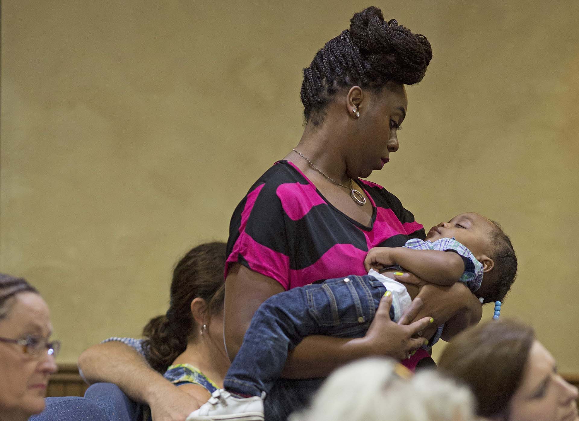 Naomi Clark, 27, holds her sleeping son, 1-year-old Caylei Clark, during services at South Walker Baptist Church in Walker, La., Sunday, Aug. 21, 2016. Clark said she moved to Walker two years ago with her husband who is a truck driver. Her and her two children were with her husband in the truck when the flood struck Walker last week. (AP Photo/Max Becherer)