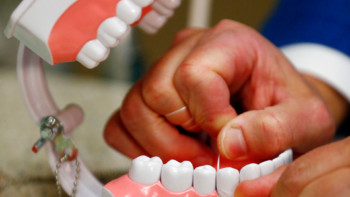 Dr. Wayne Aldredge, president of the American Academy of Periodontology, demonstrates how dental floss should be used in Holmdel, N.J. Aldredge says many people use floss incorrectly, moving it in a sawing motion instead of up and down the sides of the teeth. (AP Photo/Julio Cortez)
