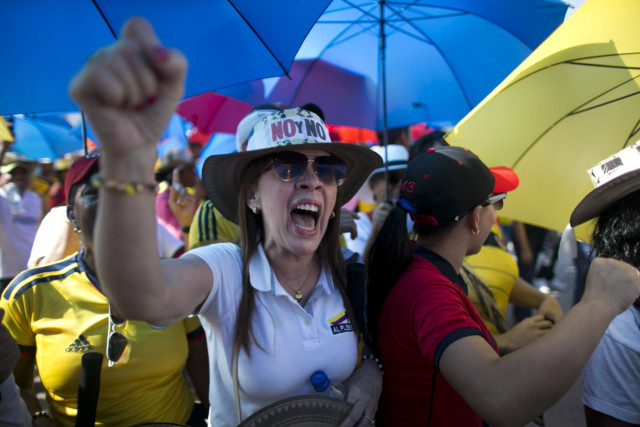 A demonstrator yells "No to the plebiscite" to protest the government's peace agreement with the Revolutionary Armed Forces of Colombia (FARC), to be signed later in the day in Cartagena, Colombia, Monday, Sept. 26, 2016. Colombians will be given the final say on endorsing or rejecting the accord in an Oct. 2 referendum. (AP Photo/Ariana Cubillos)