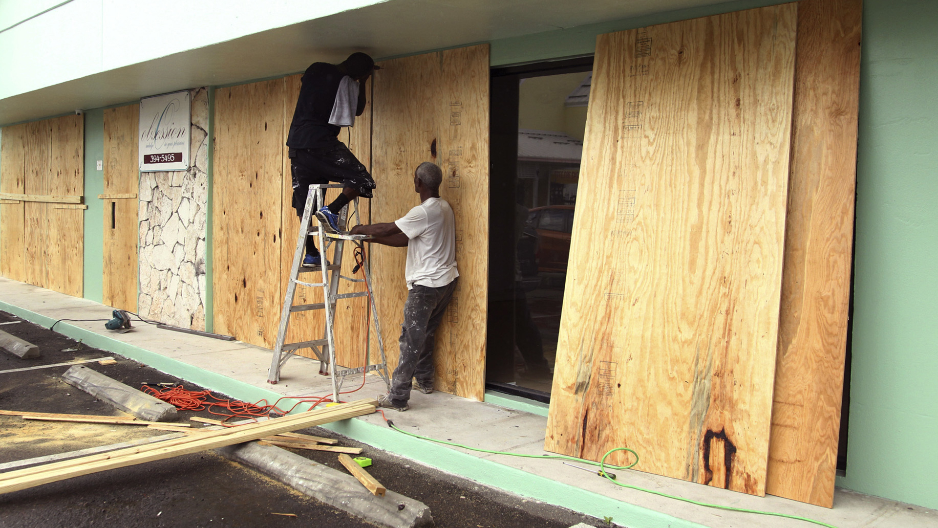 Charles Charry, on ladder, and Colin Dean secure plywood over the windows of Obsession Design clothing store in preparation for the arrival of Hurricane Matthew in Nassau, Bahamas, Wednesday, Oct. 5, 2016. Forecasters said the storm was on track to roll directly over the capital city before nearing the Florida coast. (AP Photo/Tim Aylen)