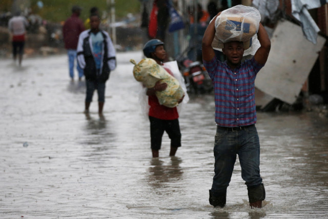 People carry their belongings as they wade across a flooded street while Hurricane Matthew passes through Port-au-Prince, Haiti