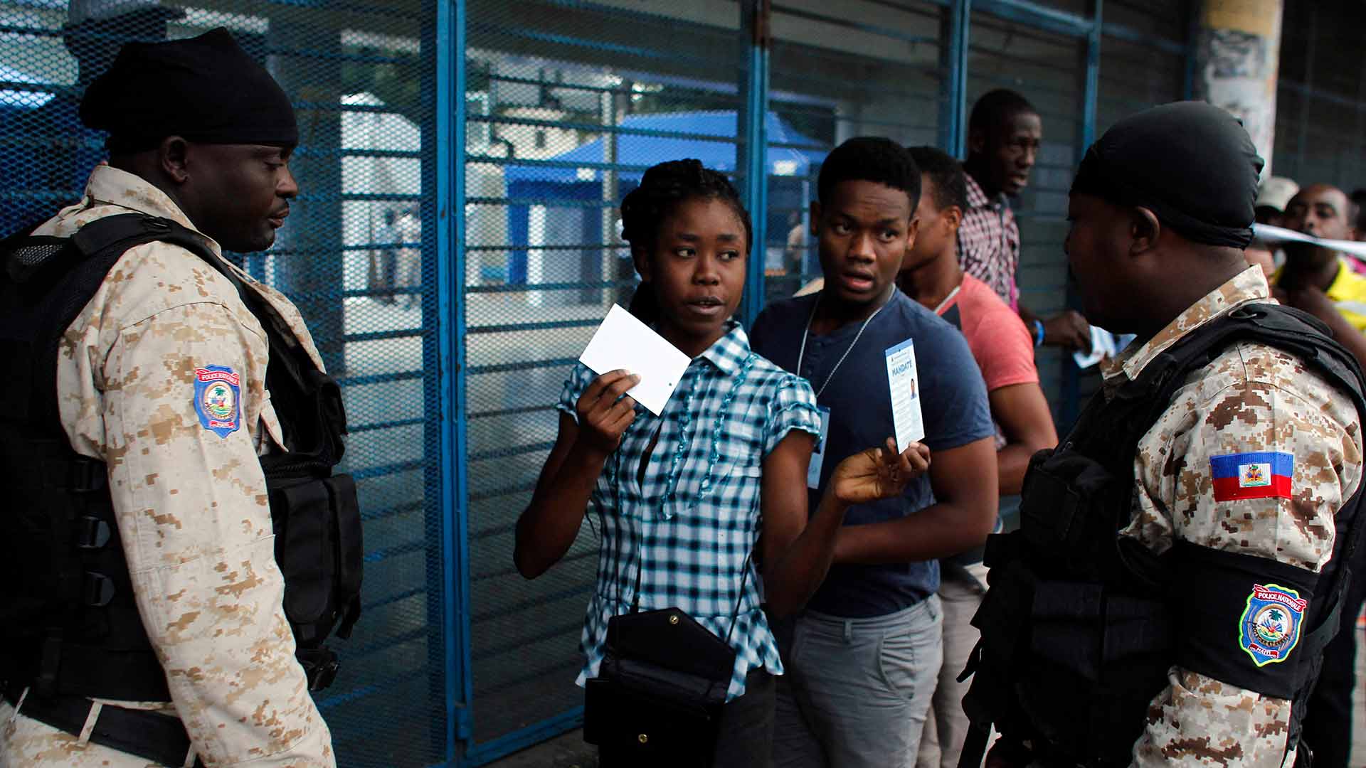A voter shows her electoral documents to national police officers before entering a voting station in the Petion-Ville suburb of Port-au-Prince, Haiti, Sunday, Nov. 20, 2016. Haiti's repeatedly derailed presidential election got underway more than a year after an initial vote was annulled. (AP Photo/Ricardo Arduengo)