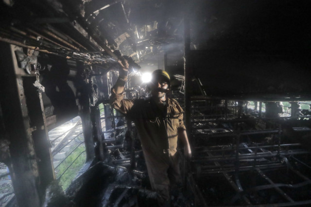 firefighter inspects the charred interiors of a vandalized train