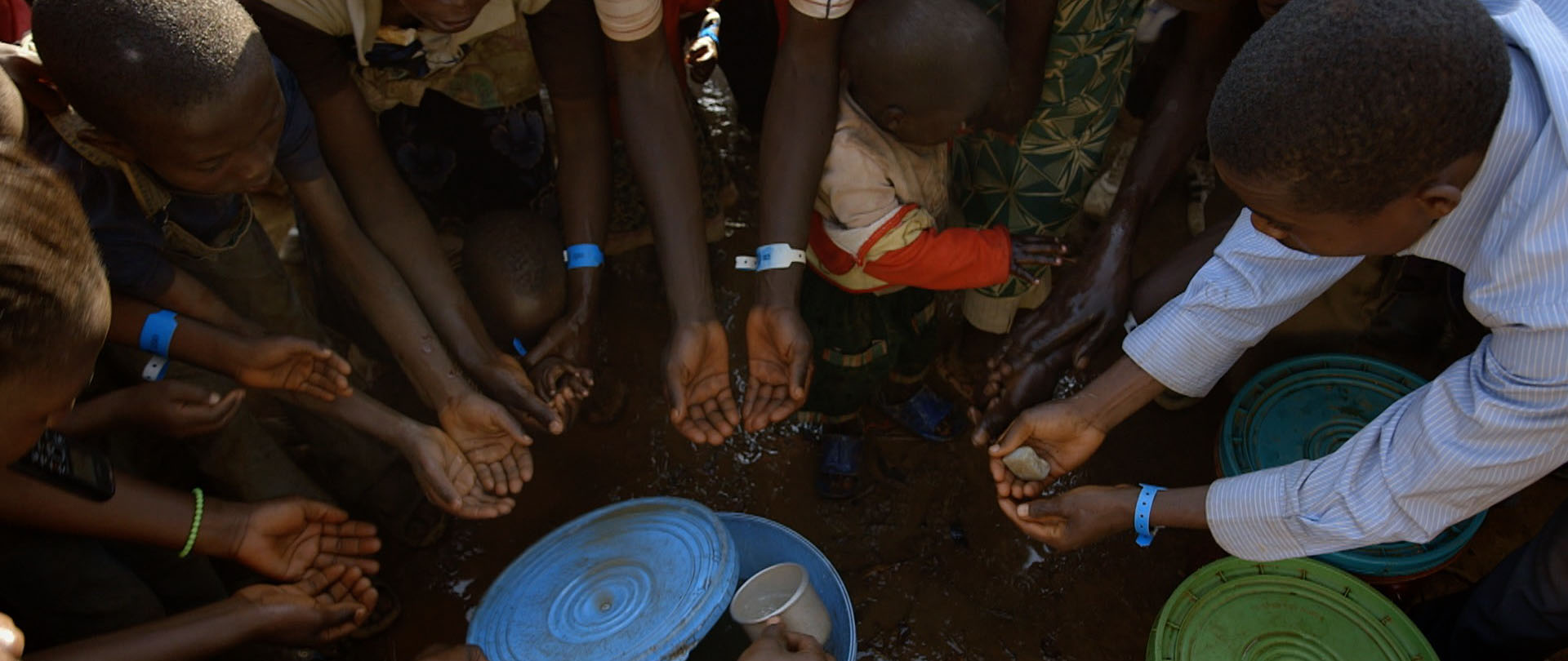 Recent arrivals to a Tanzanian camp share a bar of soap to wash hands.