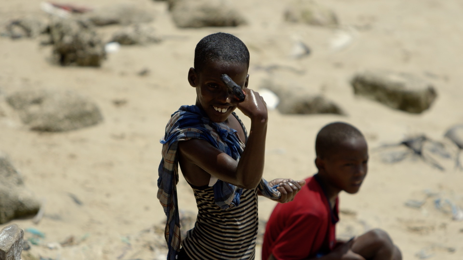 A young Somali boy plays with a gun at the beach.