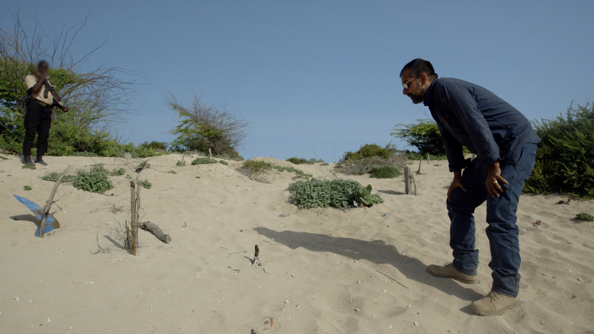 On a sandy bank, markers indicate where al Shabaab victims were buried after being executed.