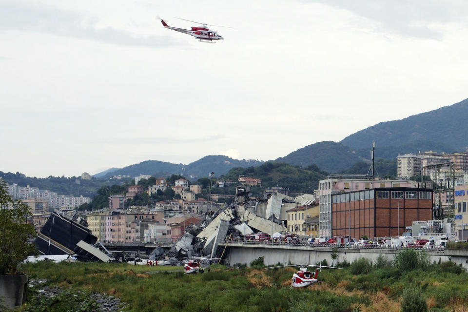 A firefighters helicopter flies over the collapsed Morandi highway bridge