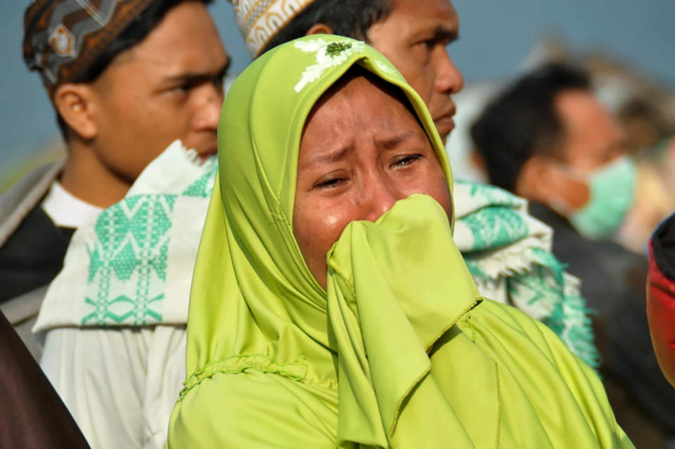 woman cries as people look at the damages after an earthquake