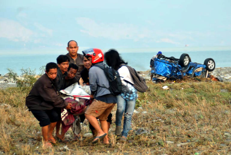 Residents carry a victim after after an earthquake and a tsunami