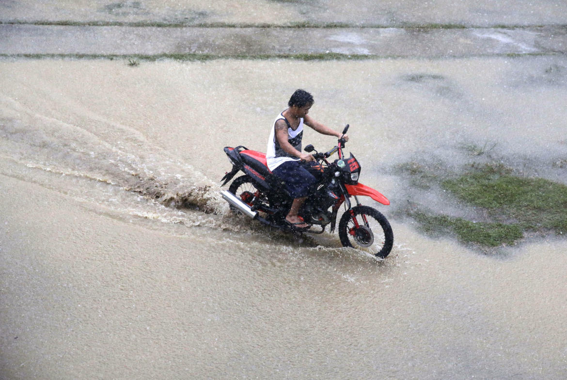 resident rides his motorcycle across a flooded area