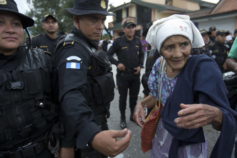 elderly Honduran migrant woman talks with Guatemalan police