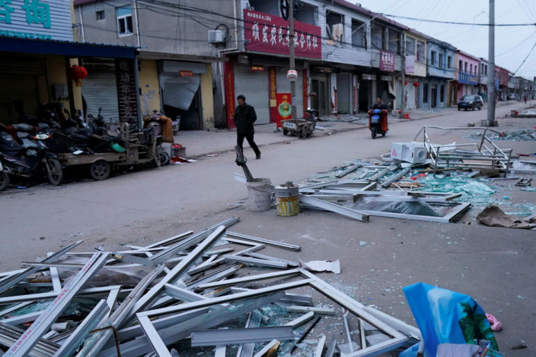 Man walks past damaged buildings following an explosion at a pesticide plant owned by Tianjiayi Chemical nearby, in Xiangshui