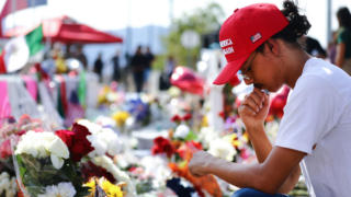 Trump supporter Jordan Flores wears a 'Make America Great Again' hat as he visits a makeshift memorial