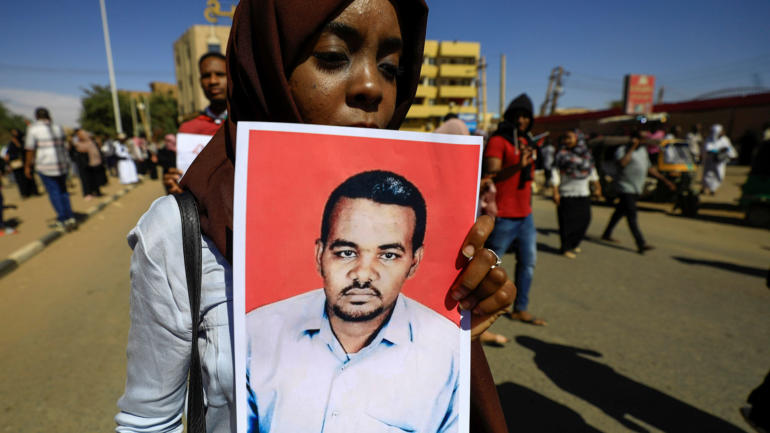 A Sudanese woman carries a portrait of the teacher Ahmed al-Khair as she celebrates outside the court in Omdurman