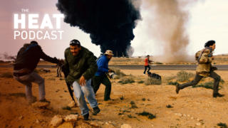 Rebel fighters run for cover in front of a burning gas storage terminal during a battle