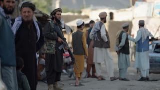 An armed Taliban is posted in a busy city in Afghanistan