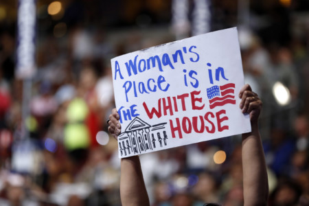 delegate holds up a sign reading "A woman's place is in the White House"