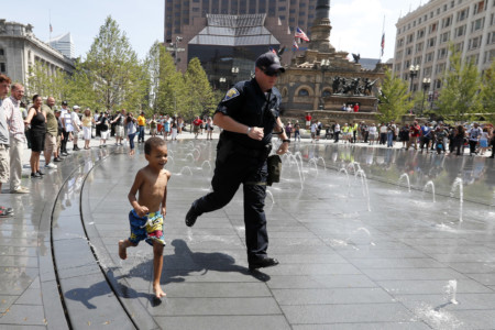 Police officer runs through a fountain with a small child