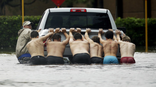 People push a stalled pickup to through a flooded street in Houston, after Tropical Storm Harvey dumped heavy rains, Sunday, Aug. 27, 2017. The remnants of Hurricane Harvey sent devastating floods pouring into Houston on Sunday as rising water chased thousands of people to rooftops or higher ground. (AP Photo/Charlie Riedel)