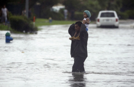 A man carries a child across a flooded street in Houston after Tropical Storm Harvey dumped heavy rains northeast Texas, Sunday, Aug. 27, 2017. The remnants of Hurricane Harvey sent devastating floods pouring into Houston Sunday as rising water chased thousands of people to rooftops or higher ground. (AP Photo/Charlie Riedel)