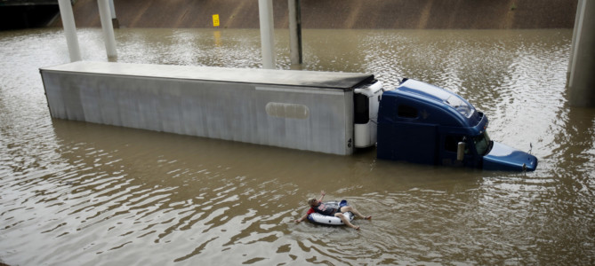 A man floats past a truck submerged on a freeway flooded by Tropical Storm Harvey on Sunday, Aug. 27, 2017, near downtown Houston. The remnants of Hurricane Harvey sent devastating floods pouring into Houston Sunday as rising water chased thousands of people to rooftops or higher ground. (AP Photo/Charlie Riedel)