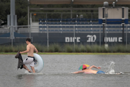 HOUSTON, TX - AUGUST 27: Riley Gardell (R) and Jacob Song make their way across a flooded parking lot on the campus of Rice University afer it was inundated with water from Hurricane Harvey on August 27, 2017 in Houston, Texas. Harvey, which made landfall north of Corpus Christi late Friday evening, is expected to dump upwards to 40 inches of rain in areas of Texas over the next couple of days. Scott Olson/Getty Images/AFP
