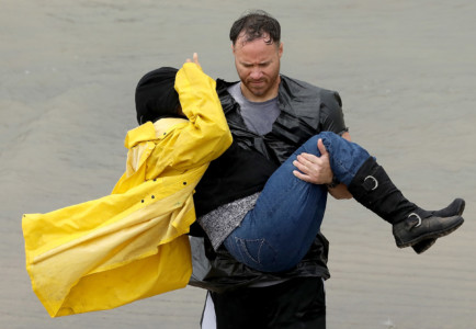 HOUSTON, TX - AUGUST 29: A volunteer carries a woman whose home was impacted by severe flooding following Hurricane Harvey in north Houston August 29, 2017 in Houston, Texas. (Win McNamee/Getty Images/AFP)