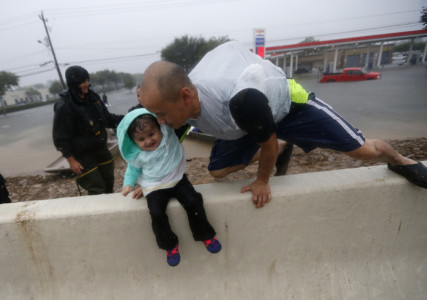 Vinh Nguyen rests his daughter Kailie, 18 months, as he hops over a highway divider after being rescued in boats by the Louisiana Department of Wildlife and Fisheries, during flooding from Tropical Storm Harvey, which hit Texas last week as a Category 4 hurricane in Houston, Monday, Aug. 28, 2017. (AP Photo/Gerald Herbert)