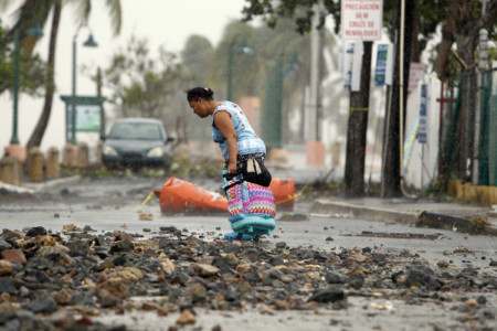 A woman pulls a travel case on a rock scattered road in the aftermath of Hurricane Irma in Fajardo, Puerto Rico, on September 7, 2017. (AFP PHOTO / Ricardo ARDUENGO)