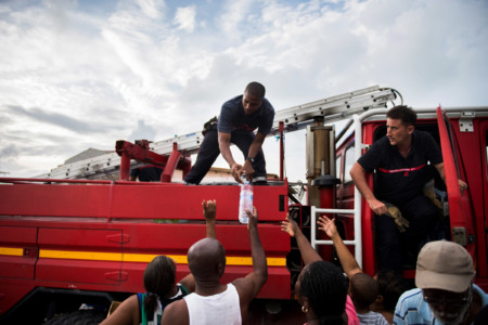 French firemen provide bottles of water to inhabitants of the Sandy Ground area of Marigot, on September 10, 2017 on Saint-Martin island, devastated by Hurricane Irma. (AFP PHOTO / Martin BUREAU)